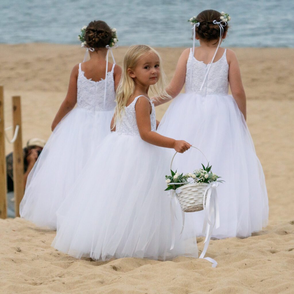 two little girls in white dresses on the beach