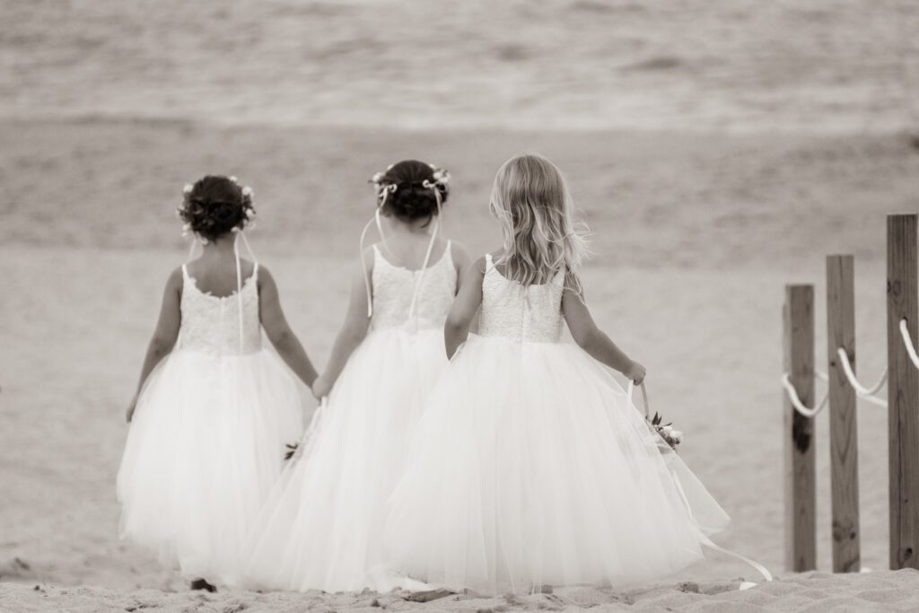 two little girls in dresses walking on the beach