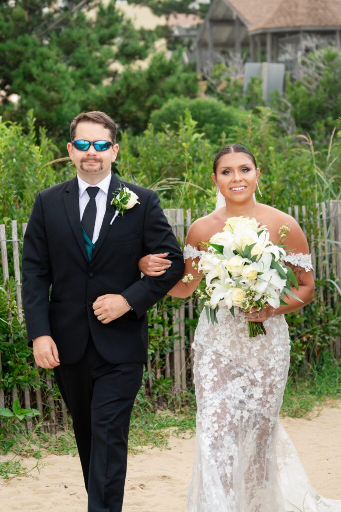 a bride and groom walking down the beach