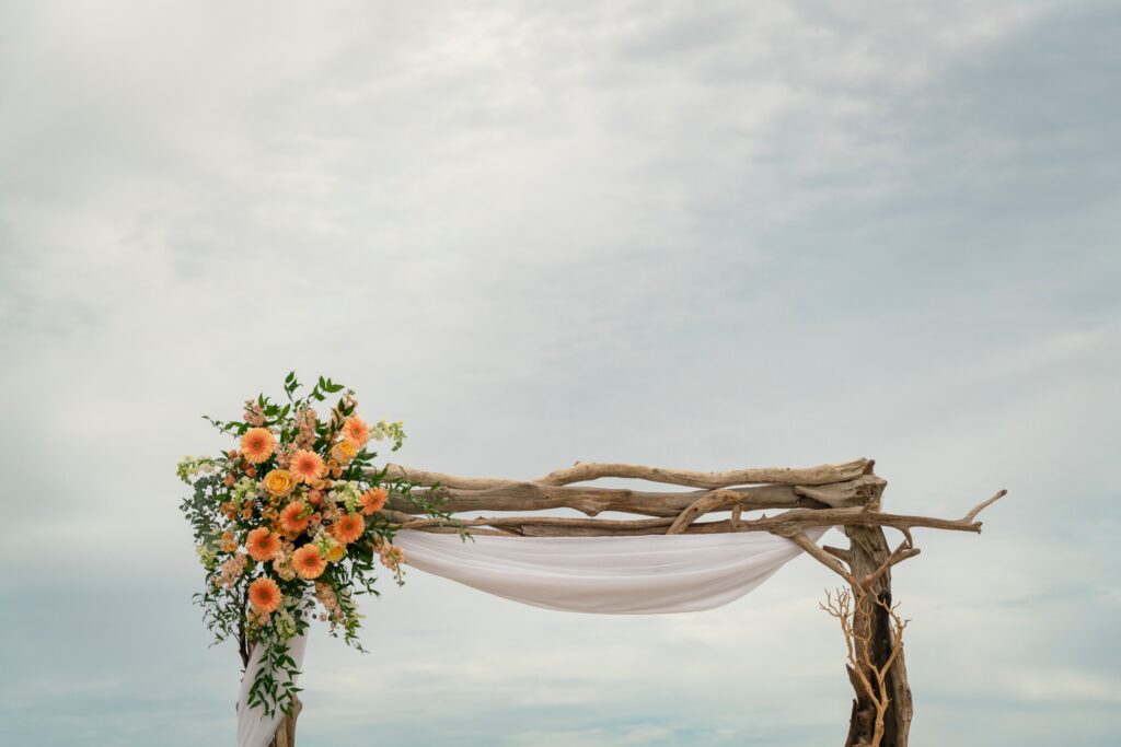 an outdoor wedding setup with a white drape and orange flowers