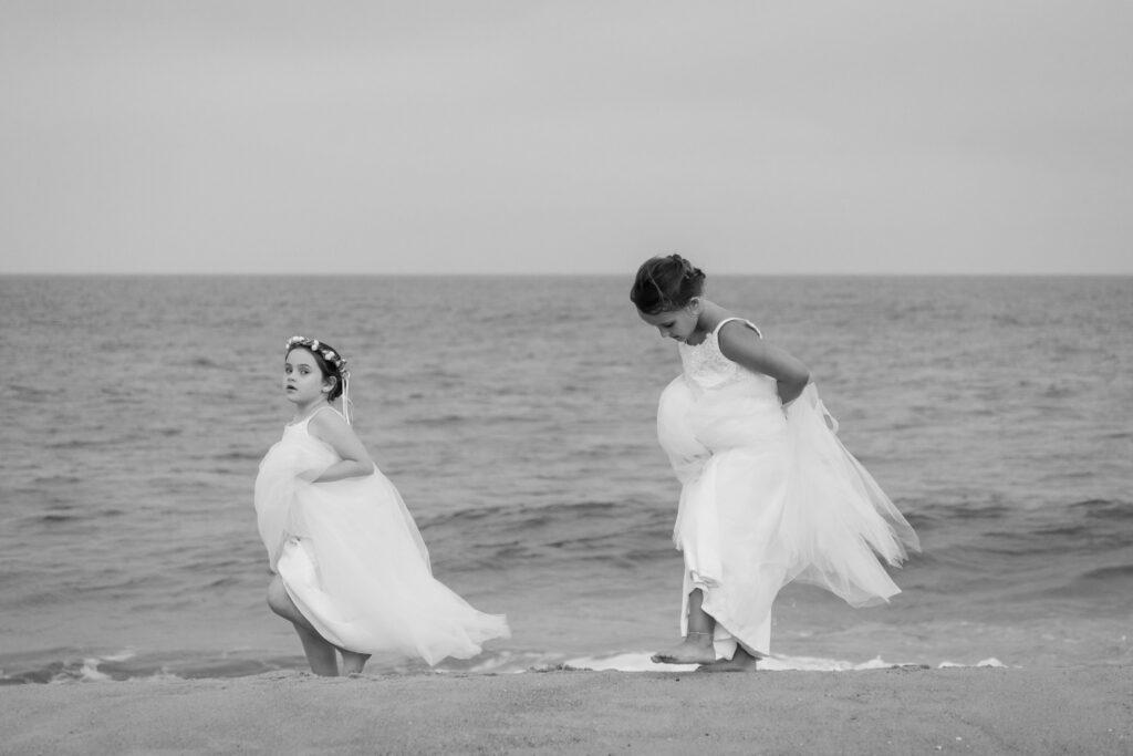 two women in white dresses standing on the beach