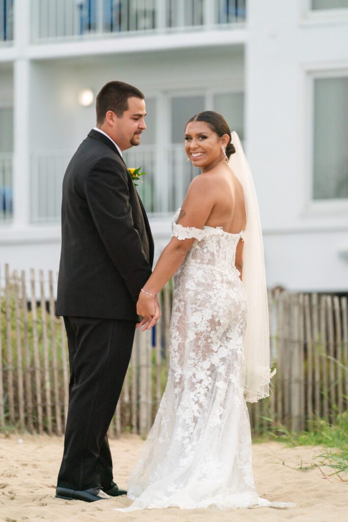 a bride and groom holding hands on the beach