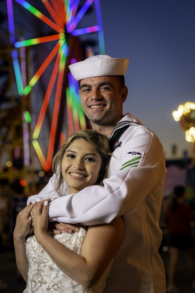 a man and a woman hugging in front of a ferris wheel