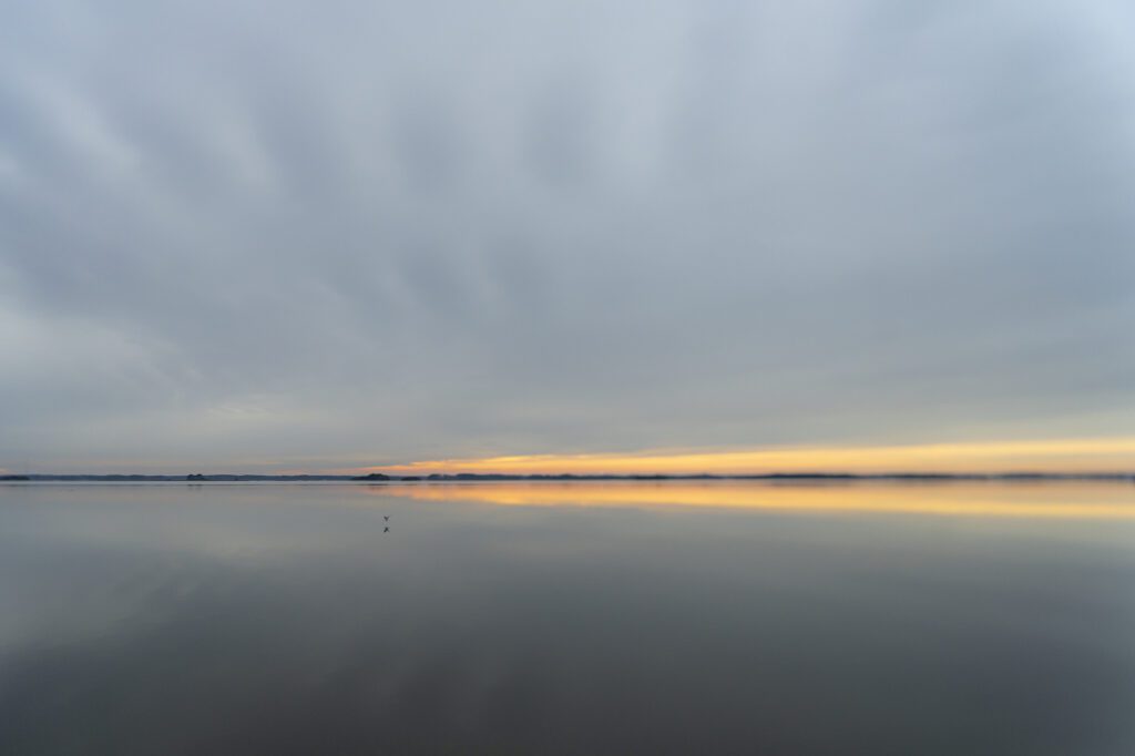 a body of water with clouds in the sky