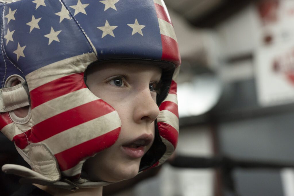 a young boy wearing an american flag boxing helmet