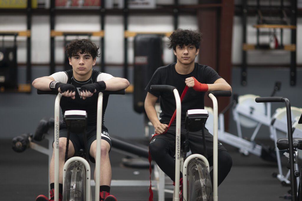 two men sitting on exercise bikes in a gym