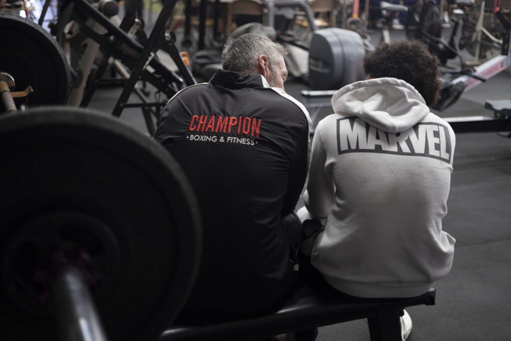 two people sitting on a bench in a gym