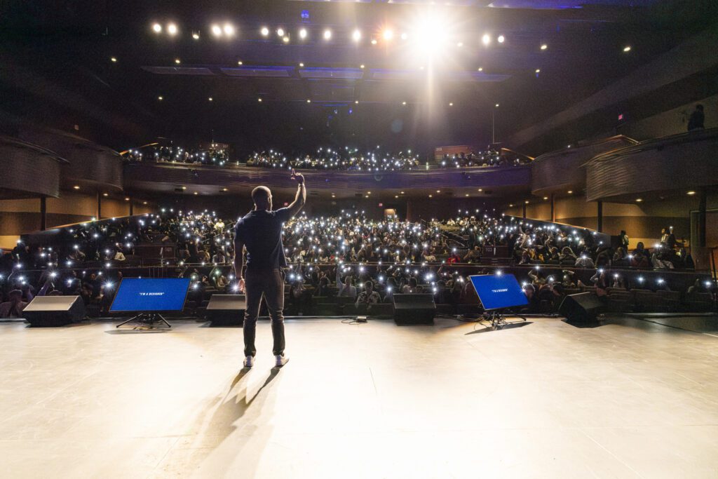 a man standing on a stage with his arms up