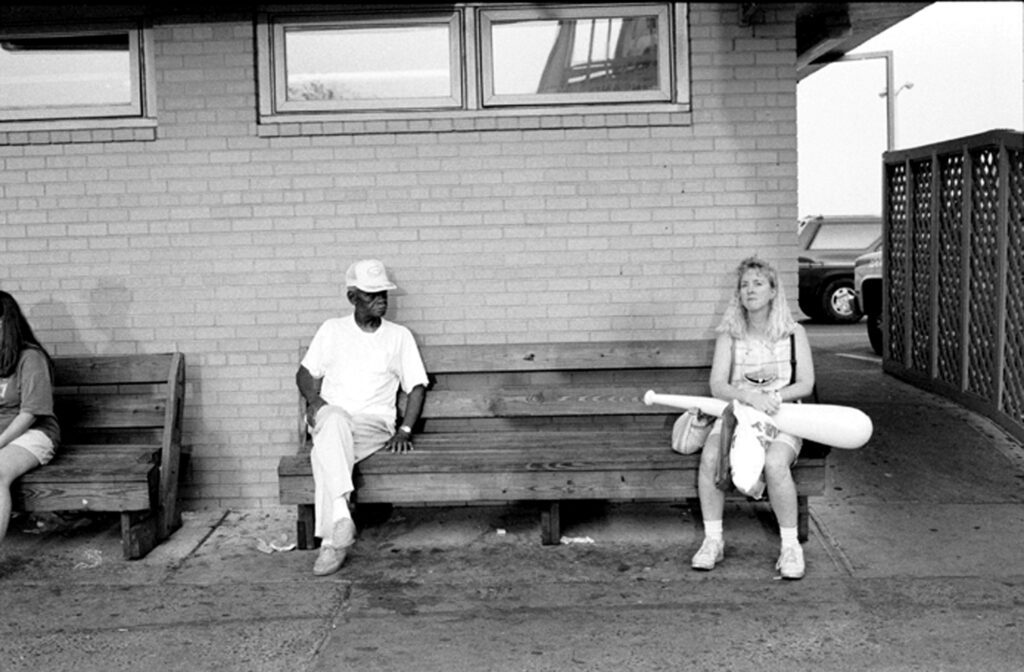 a black and white photo of three people sitting on a bench