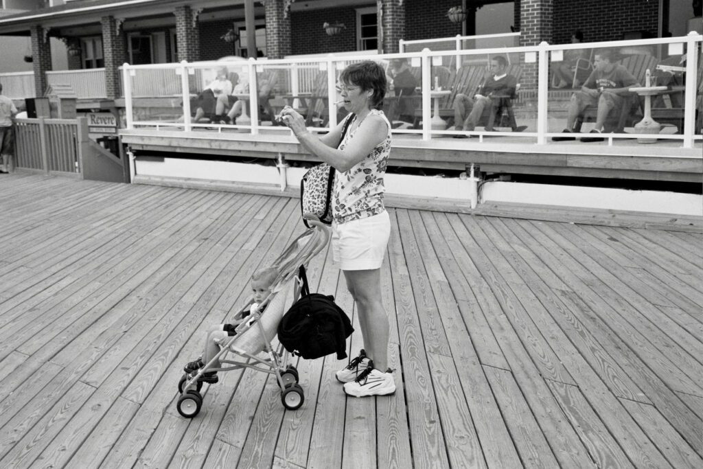 a woman standing on a boardwalk with a stroller