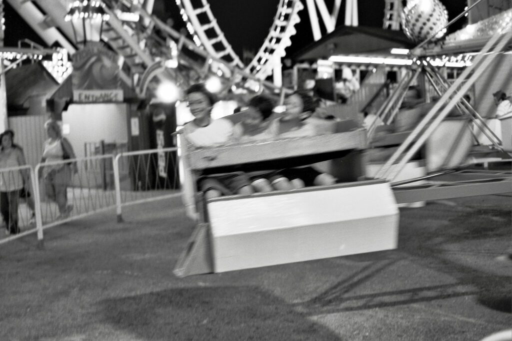 a black and white photo of people riding a merry go round