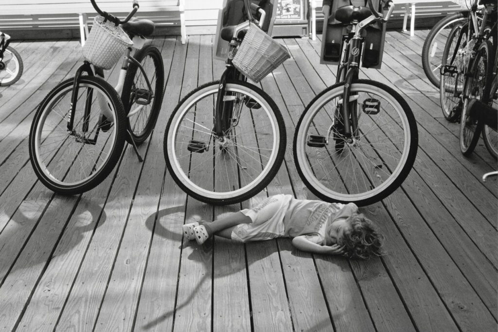 a girl laying on the ground next to three bikes