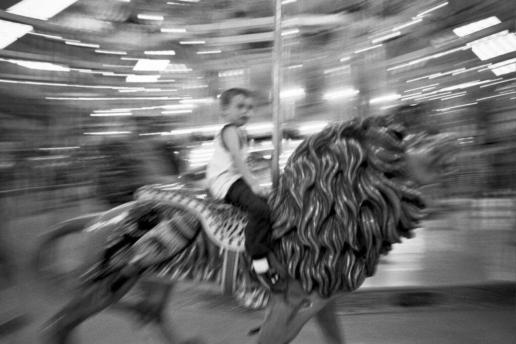 a young girl riding on the back of a carousel horse