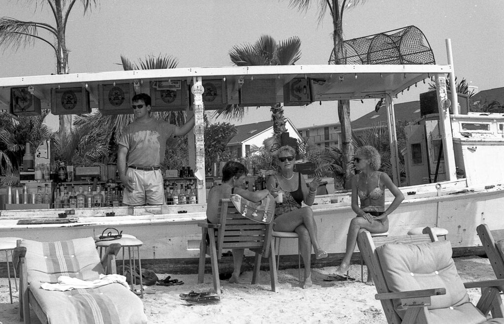 a group of people sitting at a bar on the beach