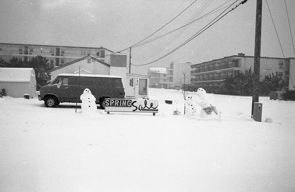 a couple of snowmen standing next to a sign
