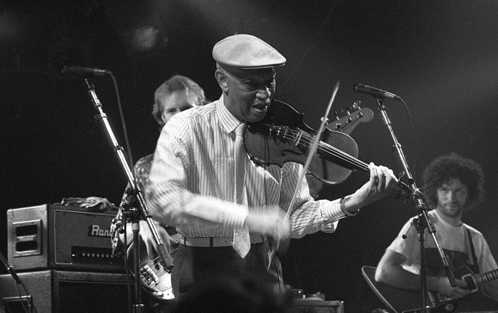 a black and white photo of a man playing a violin