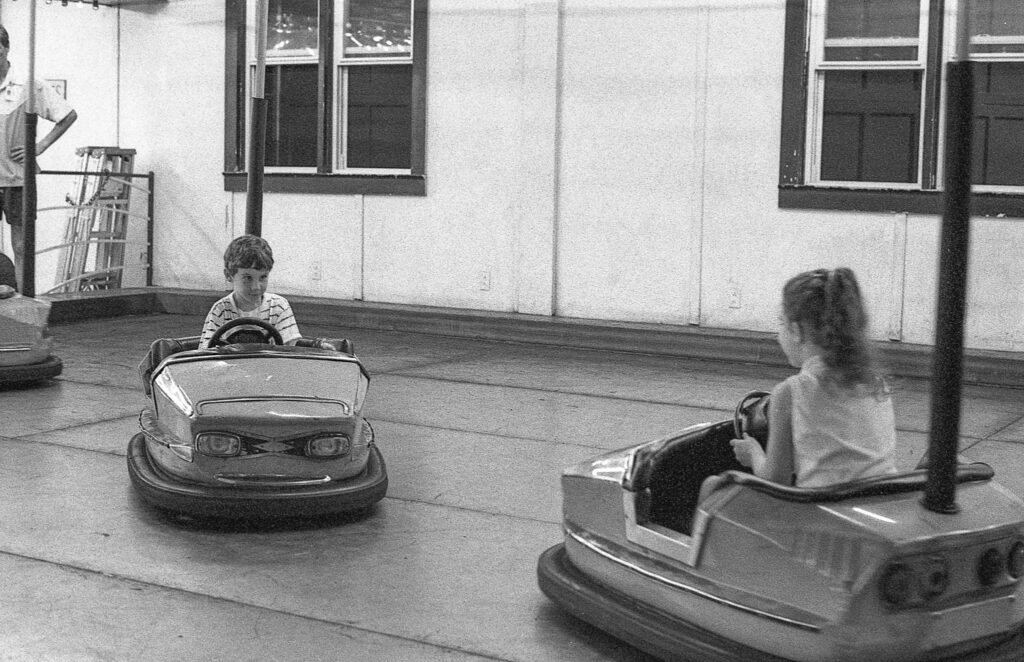 two children are riding bumper cars on the street