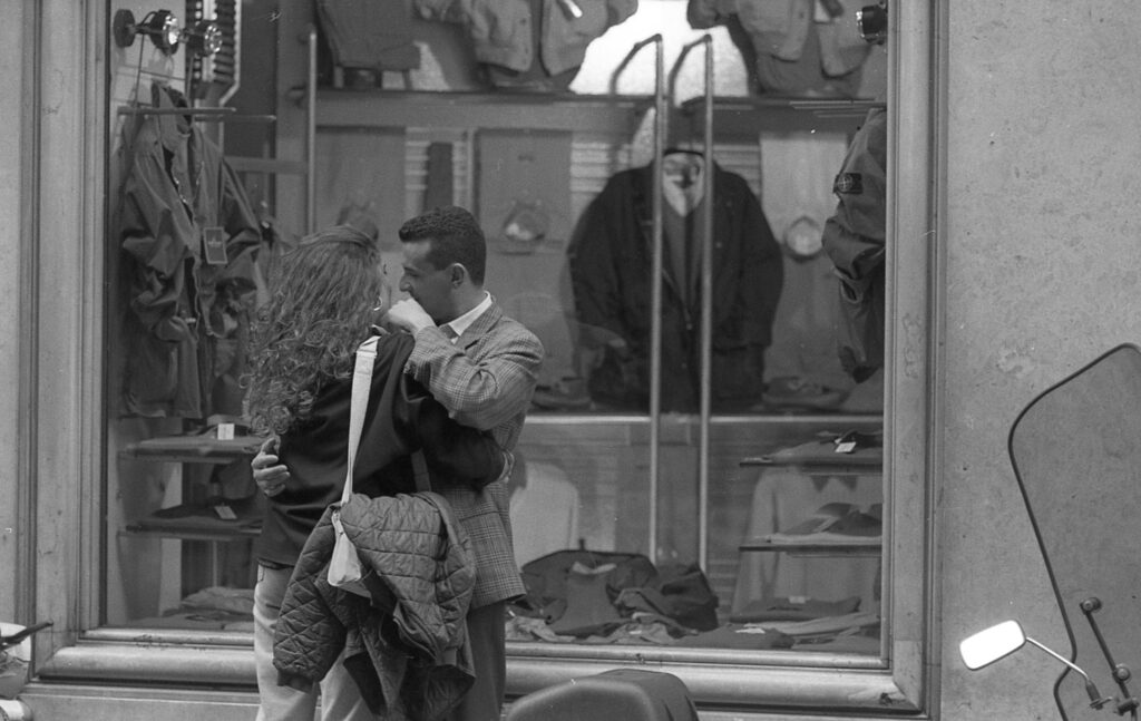 a man and woman walking past a clothing store window