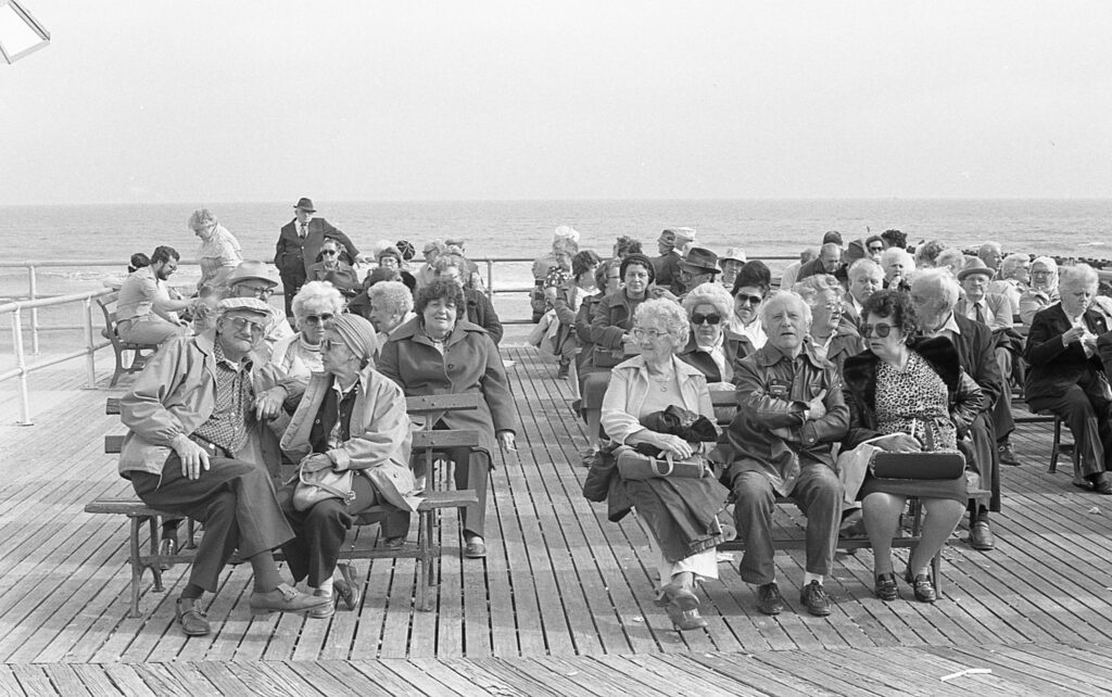 a group of people sitting on top of a wooden pier