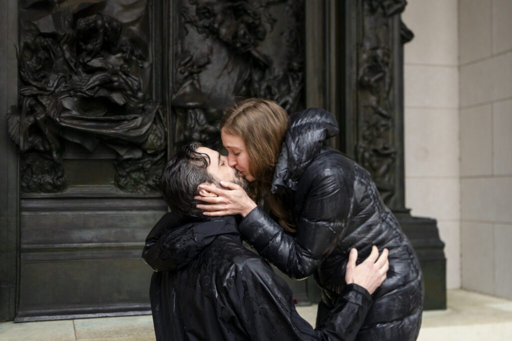 a man and woman kissing each other in front of a building