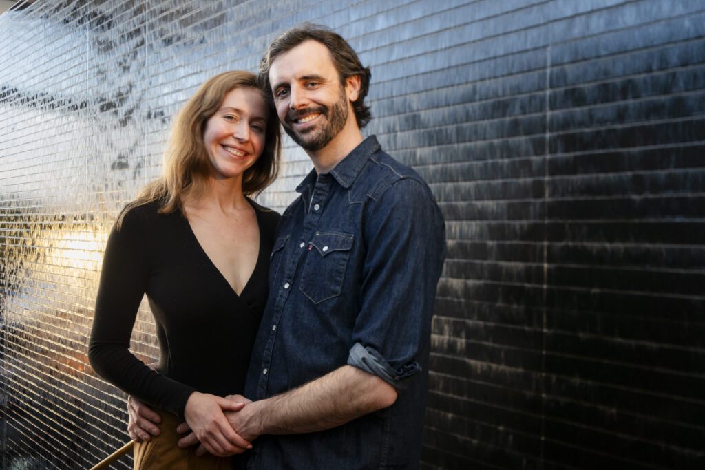 a man and woman standing in front of a wall