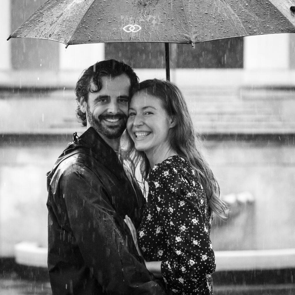 a man and woman hugging under an umbrella in the rain