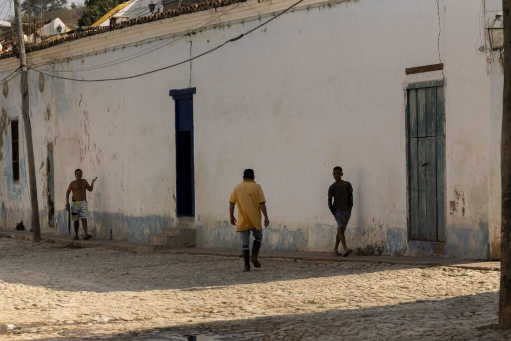 a group of men walking down a street next to a white building