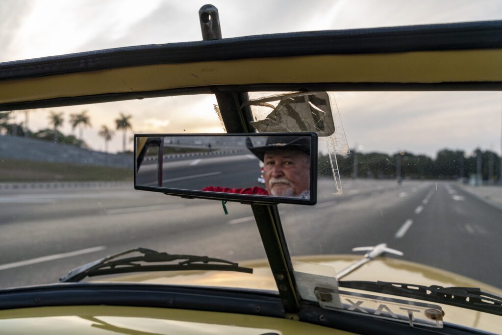 a man driving a car with a rear view mirror