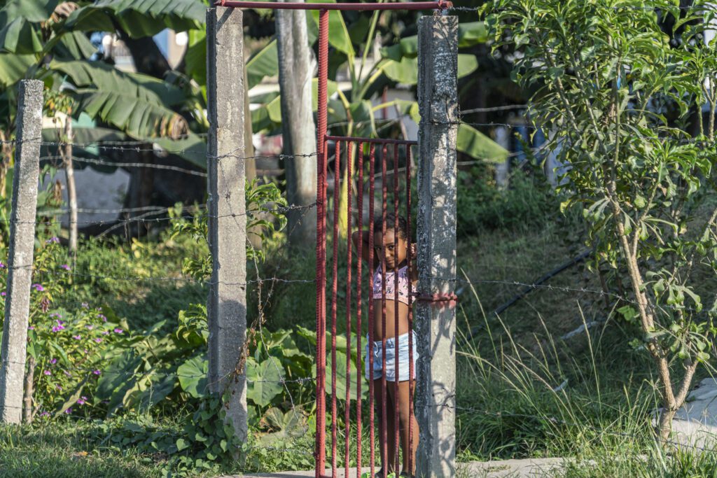 a young girl standing in front of a gate