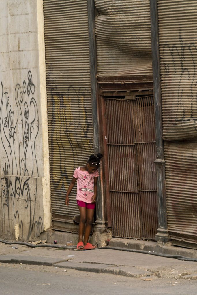 a little girl standing in front of a building with graffiti on it
