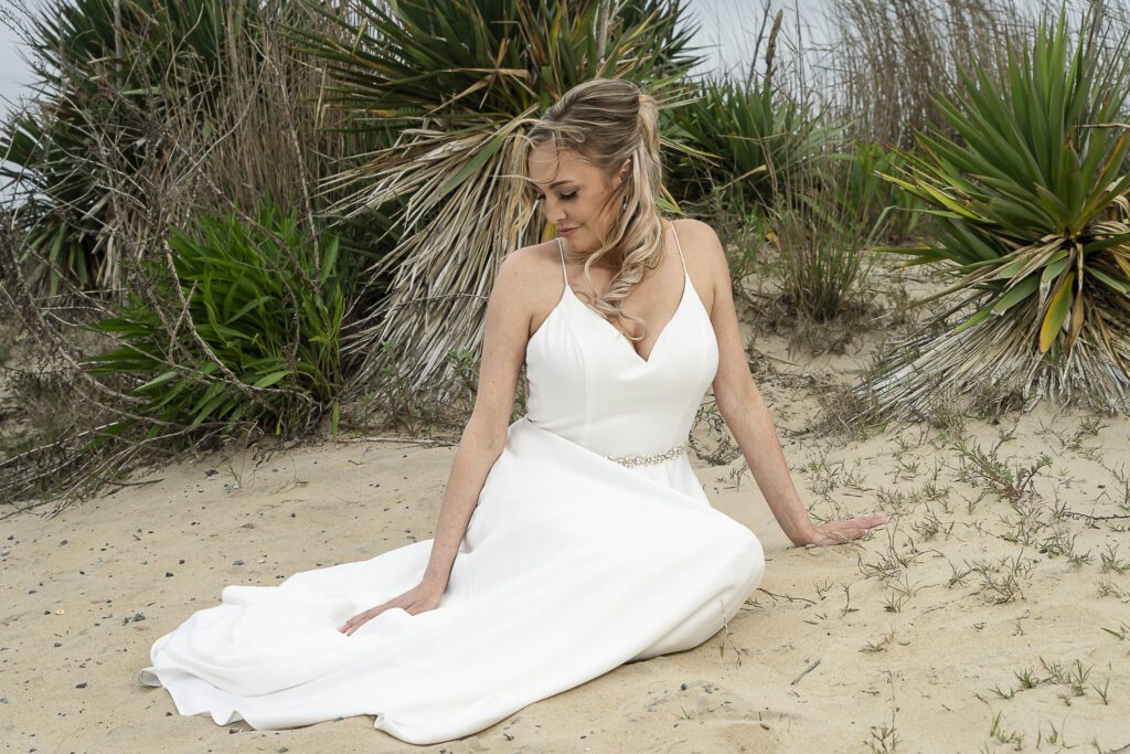 a woman in a white dress sitting on a beach