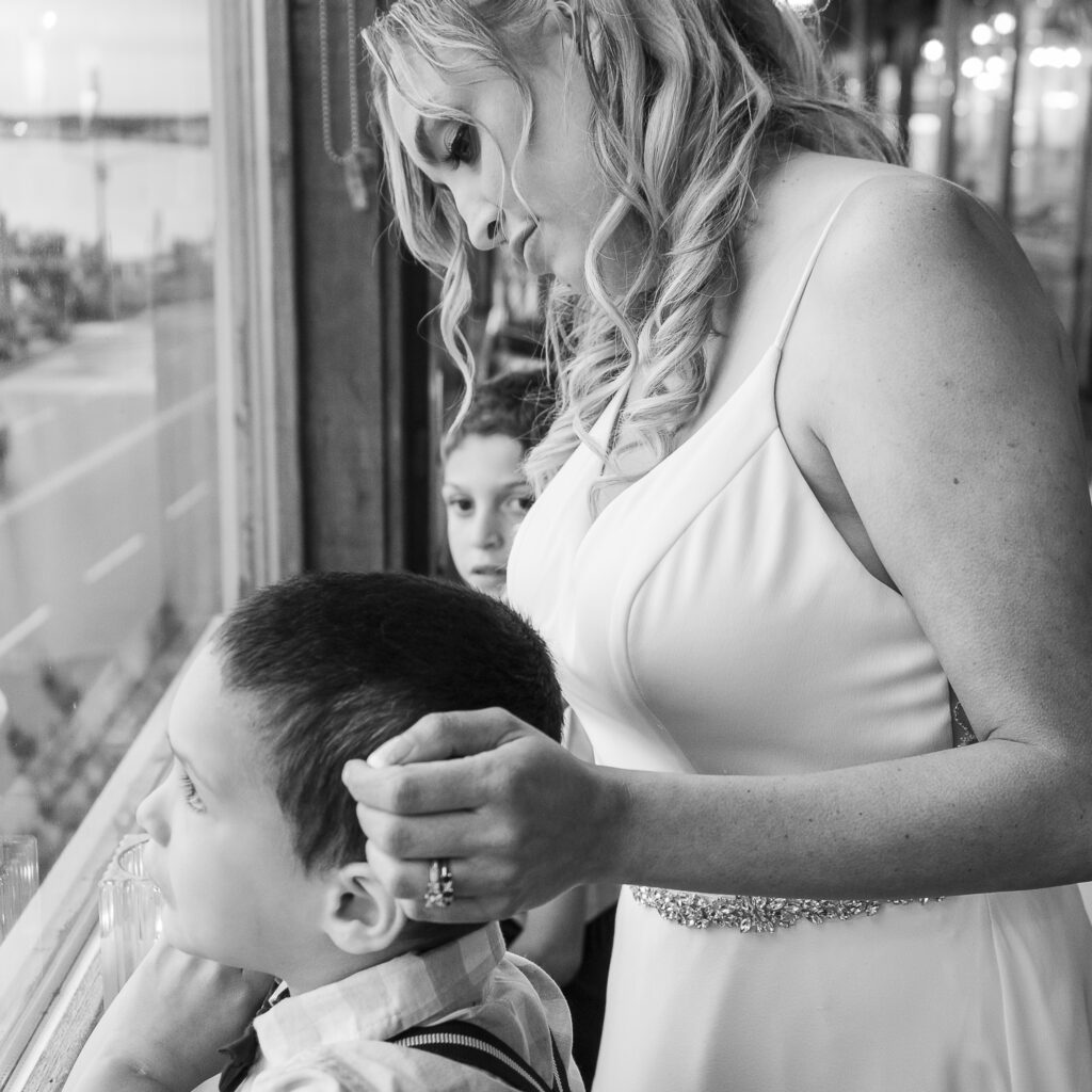 a woman combs a boy's hair in front of a window