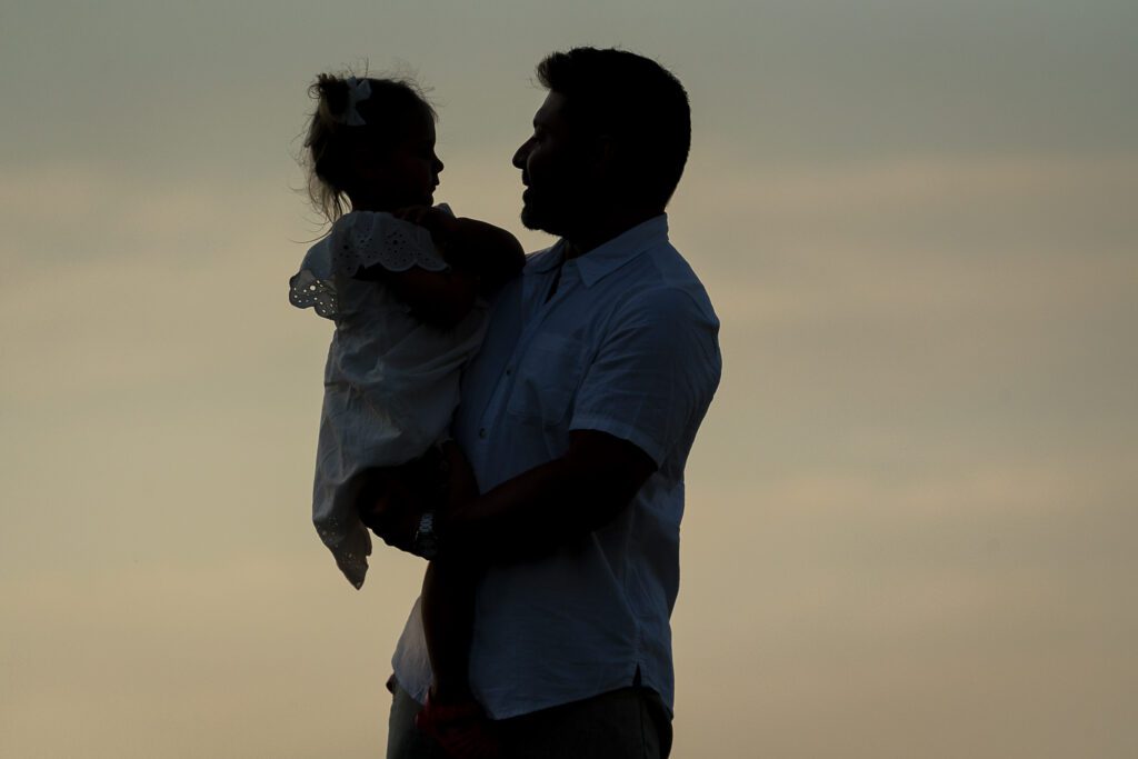 a silhouette of a man holding a little girl