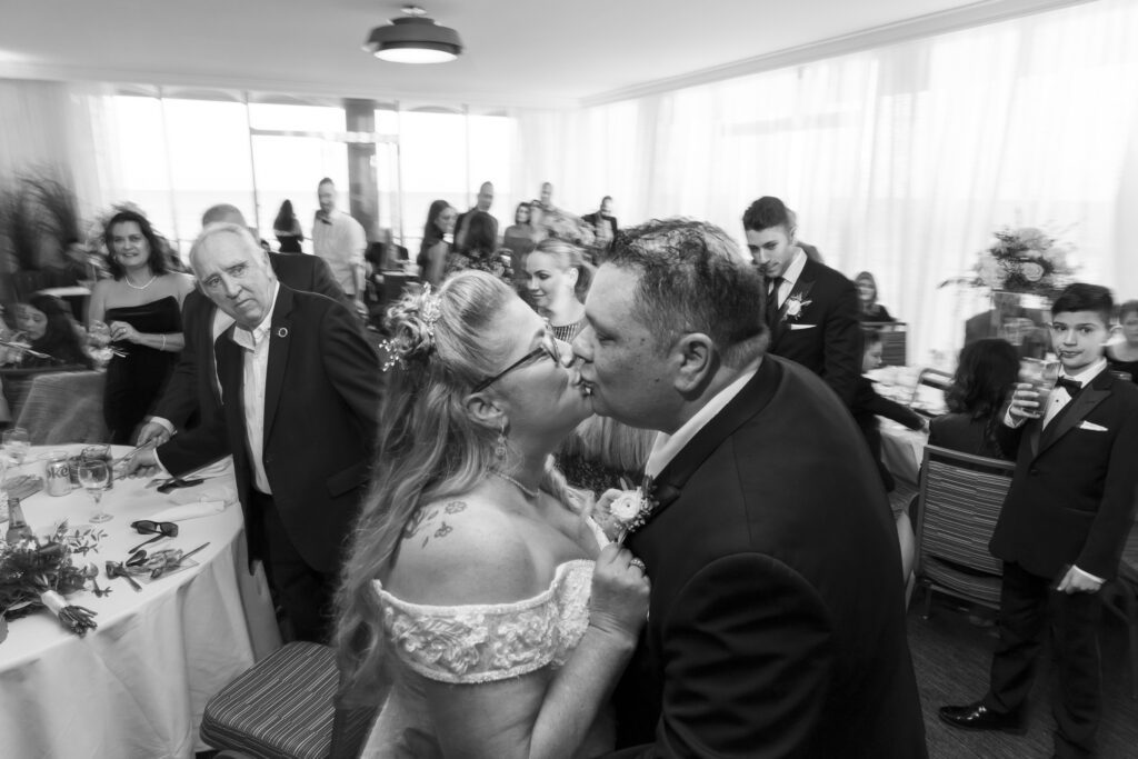 a bride and groom kissing in front of a crowd of people