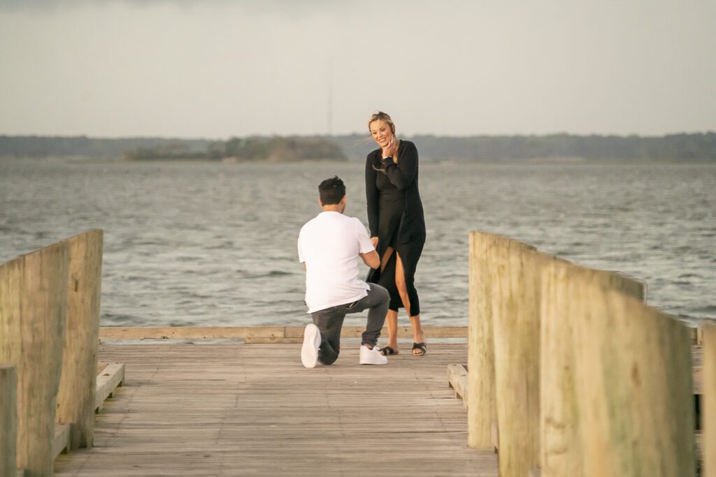 a man kneeling down next to a woman on a pier