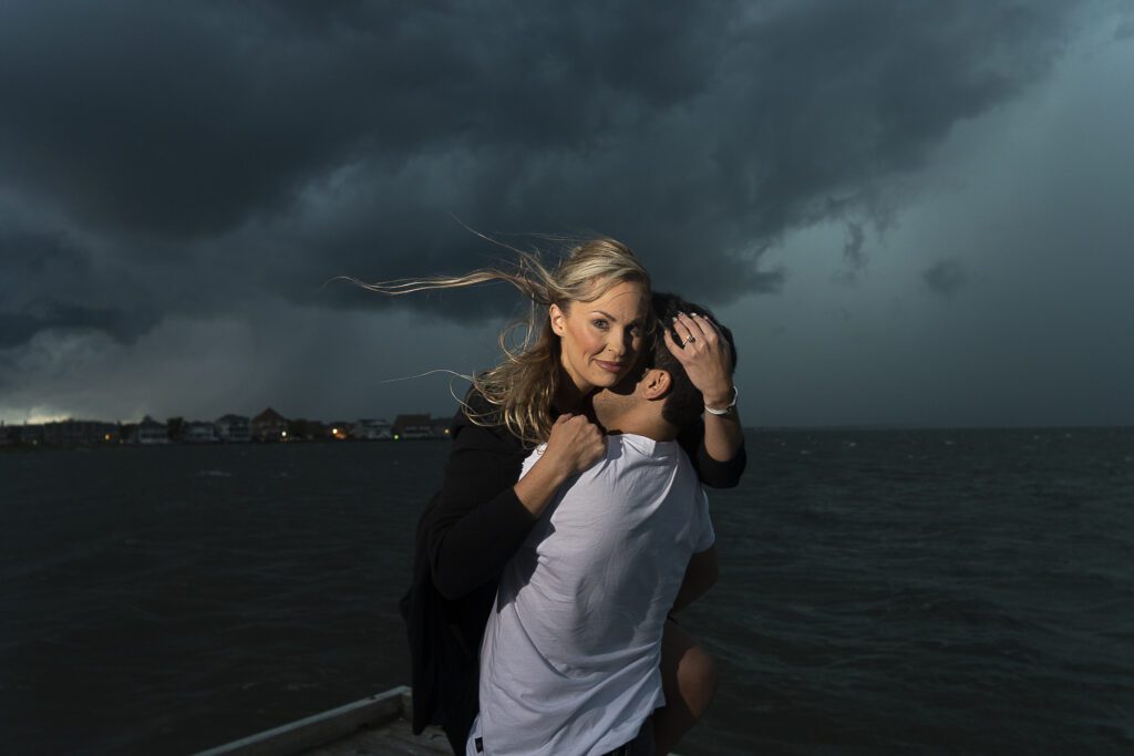 a man carrying a woman on a boat under a stormy sky