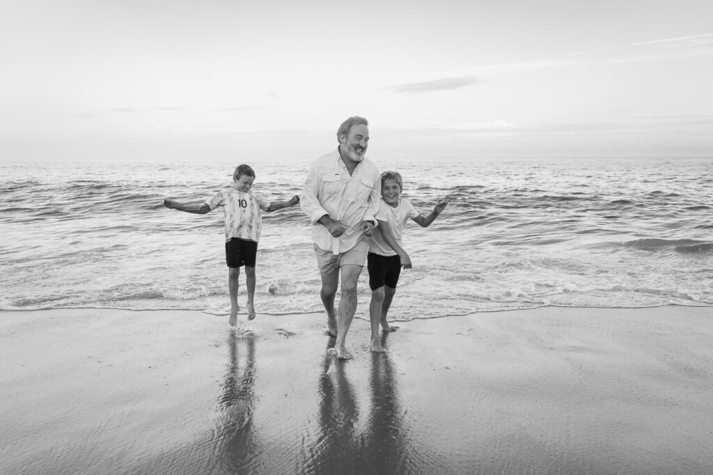 a man and two children running on the beach