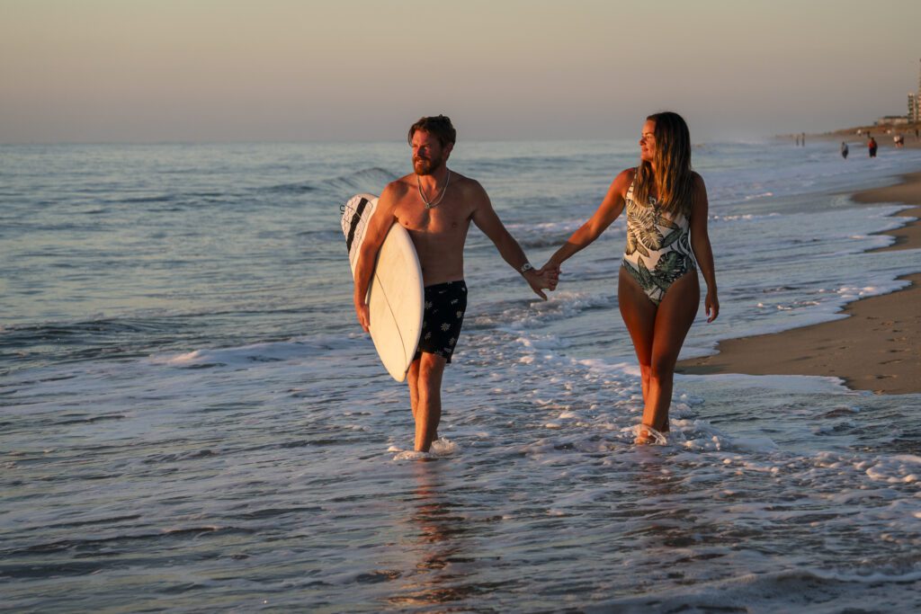 a man and a woman walking on the beach holding hands