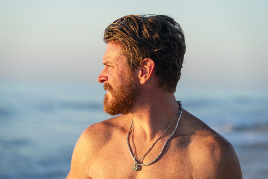 a man with a beard standing on the beach