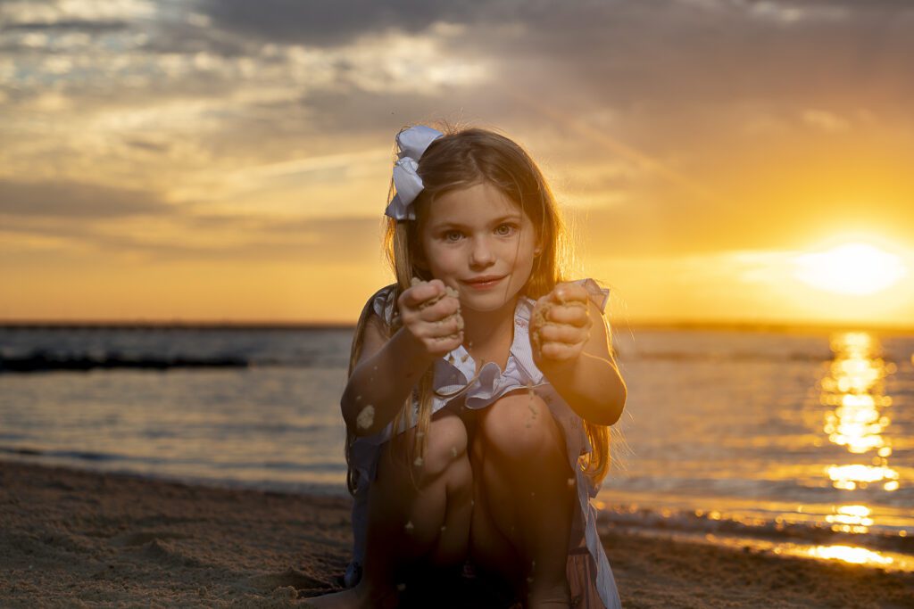 a girl sitting on the beach at sunset