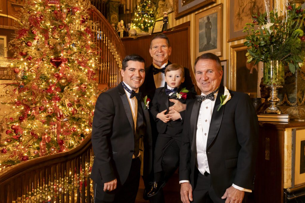 a group of men standing next to each other in front of a christmas tree