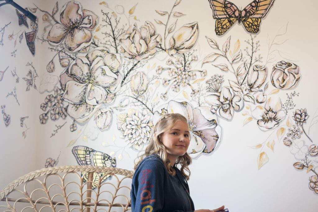 a girl standing in front of a wall with butterflies on it