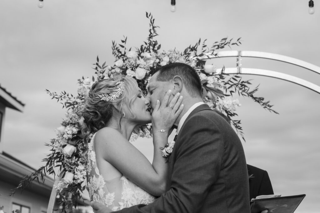 a bride and groom kissing in front of a wedding arch