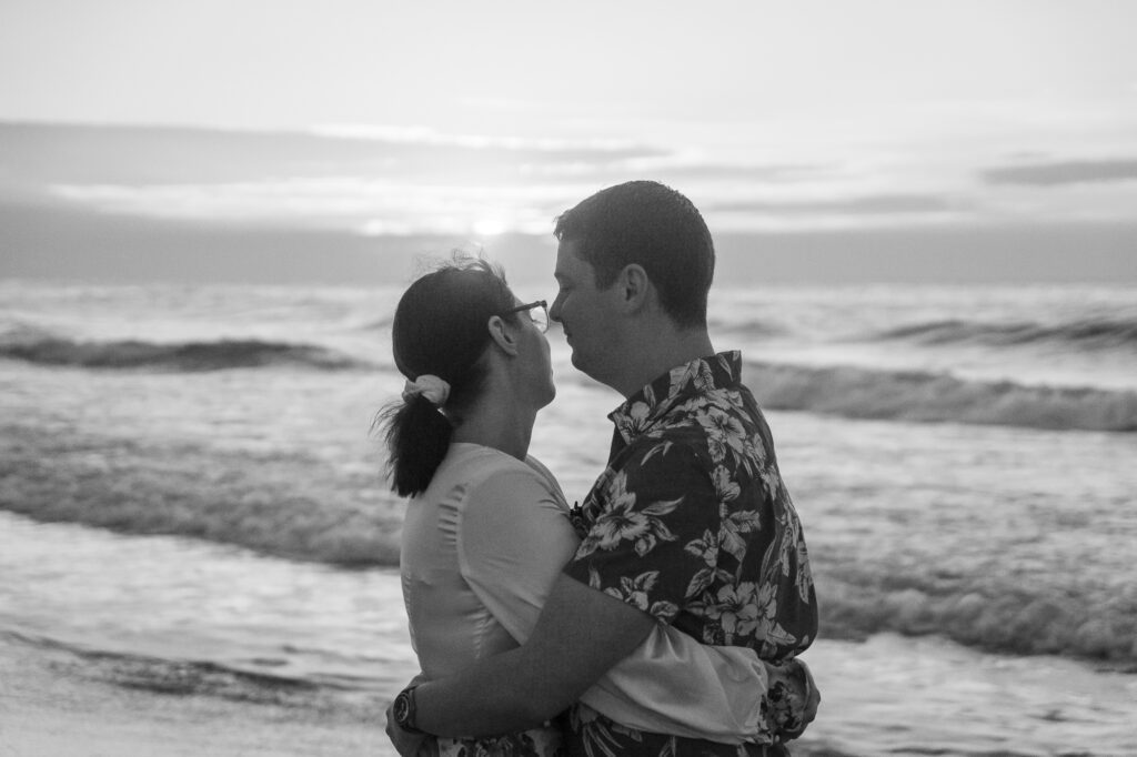 a man and a woman kissing on the beach