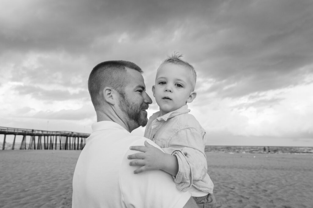 a man holding a baby on the beach