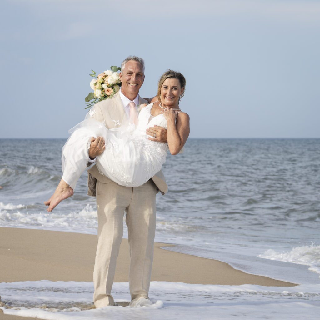 a bride carrying her groom on the beach