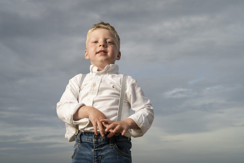 a young boy standing in a field with his hands on his hips