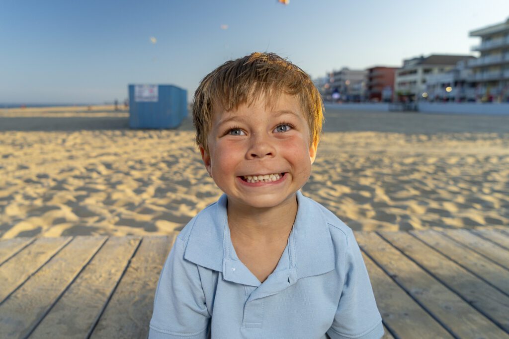 a young boy sitting on a wooden deck at the beach
