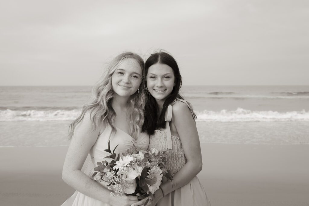 two beautiful young women standing next to each other on a beach