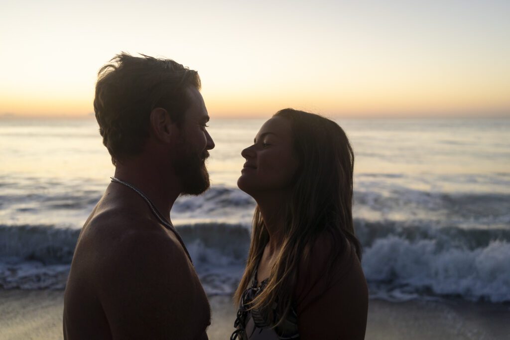 a man and a woman standing next to each other on a beach